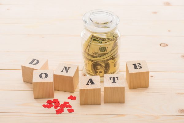 Dollar banknotes in glass jar and wooden cubes with donate lettering, donation concept
